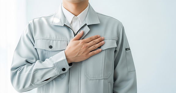 作業着を着た人物が両手を前に出していらないポーズをしています