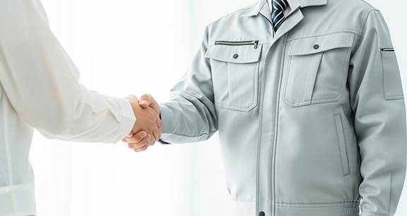 作業着を着た男女2名が拳を握りしめています